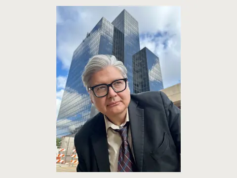 Herbert Midgley near a modern city building.