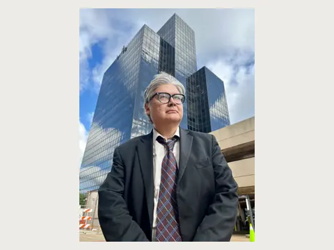 Herbert Midgley standing near a modern city building.