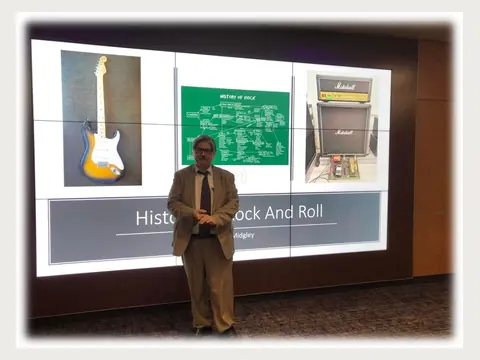 Herbert Midgley presenting a History of Rock and Roll lecture.