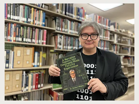 Herbert Midgley holding his published dissertation in a library.