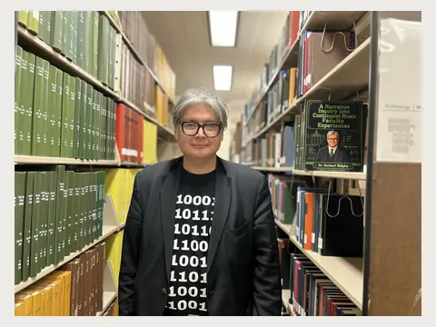 Herbert Midgley standing in a university library.