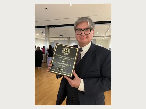 Herbert Midgley holding a university award.