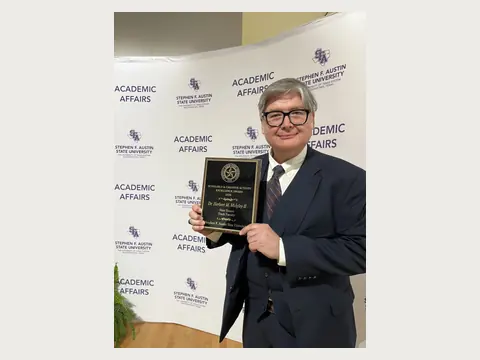 Herbert Midgley holding a university award at an academic event.