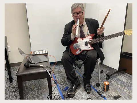 Herbert Midgley demonstrating an electric guitar and music technology.