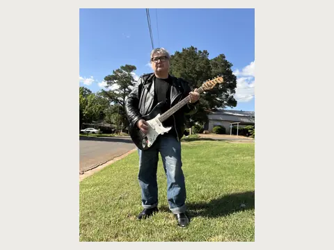 Herbert Midgley playing electric guitar outdoors.