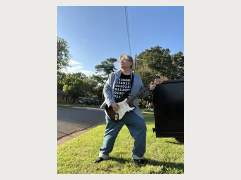 Herbert Midgley performing with an electric guitar outdoors.