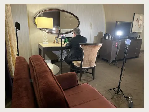 Herbert Midgley filming at a compact hotel-room set.