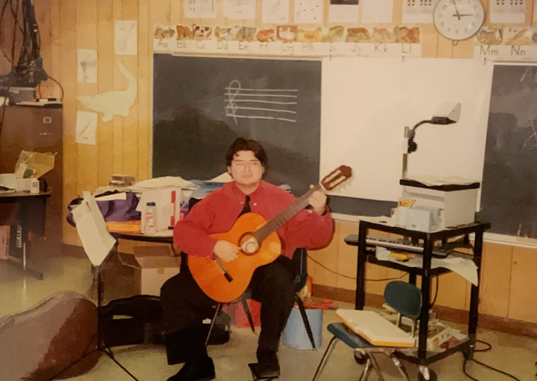 A younger Herbert Midgley teaching guitar in a classroom